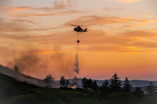 helicopter dispensing water over fire