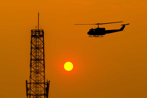 helicopter in the sky near tower during golden hours